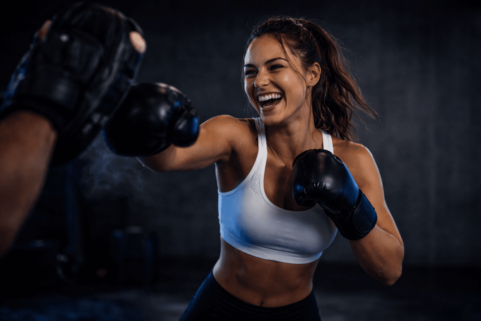 Smiling member throwing a punch during a coach-supported boxing workout at TENROUNDS